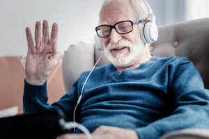 Hello to everyone. Positive nice joyful man smiling and waving his hand while greeting his family